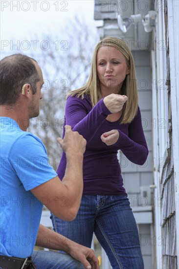 Caucasian homeowner signing to deaf repairman