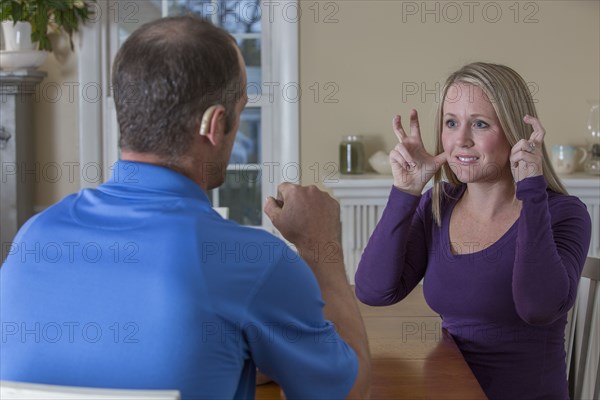 Deaf Caucasian couple signing at dinner table