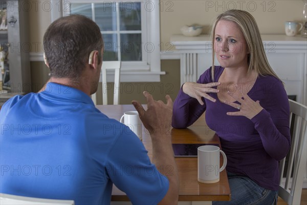 Deaf Caucasian couple signing at dinner table