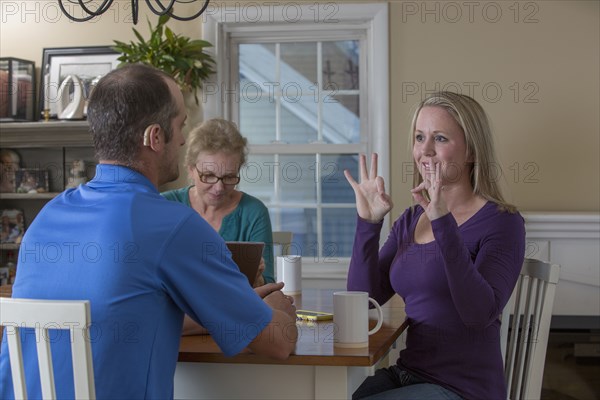 Deaf Caucasian friends signing at dinner table