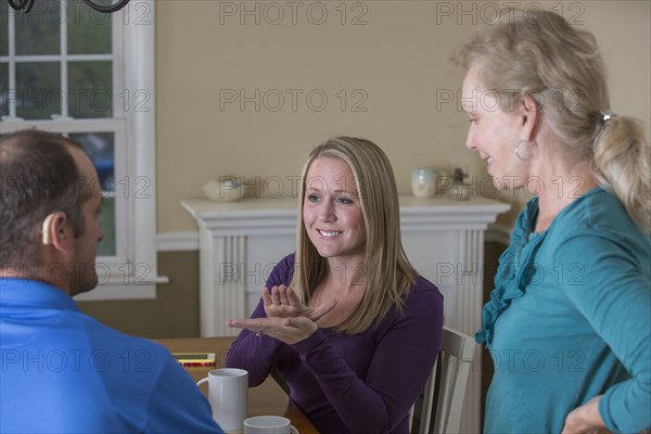 Deaf Caucasian friends signing at dinner table