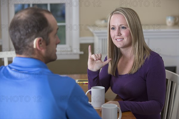 Deaf Caucasian couple signing at dinner table