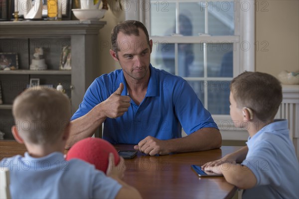 Caucasian father and sons signing at dinner table