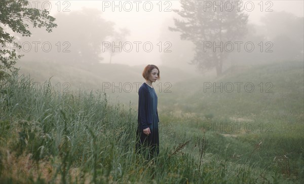 Caucasian woman standing in fog on hillside