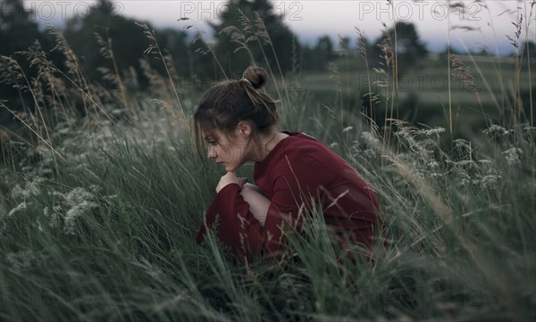 Pensive Caucasian woman sitting in tall grass