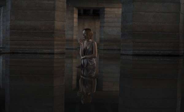 Caucasian woman standing in water smoking cigarette