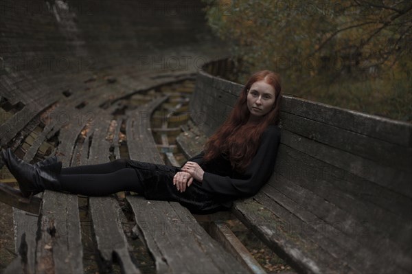 Caucasian woman sitting on rotting wooden bench