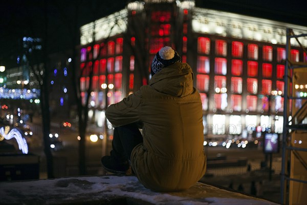 Black man wearing coat and hat in city at night