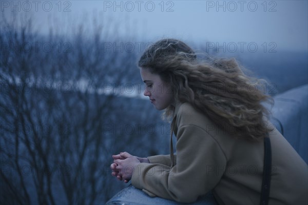 Portrait of pensive Caucasian teenage girl leaning on rooftop