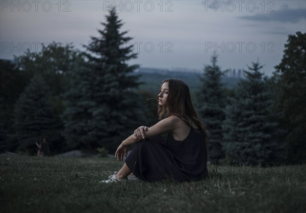Pensive Caucasian woman sitting in field of grass