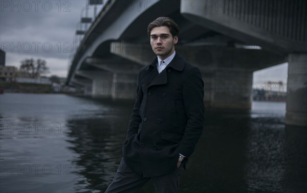 Portrait of serious Caucasian man standing under bridge