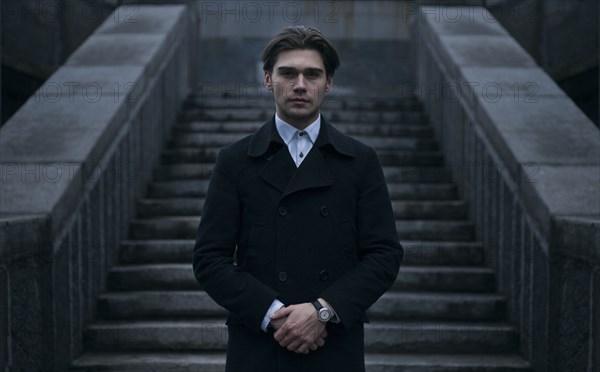 Portrait of serious Caucasian man standing near staircase