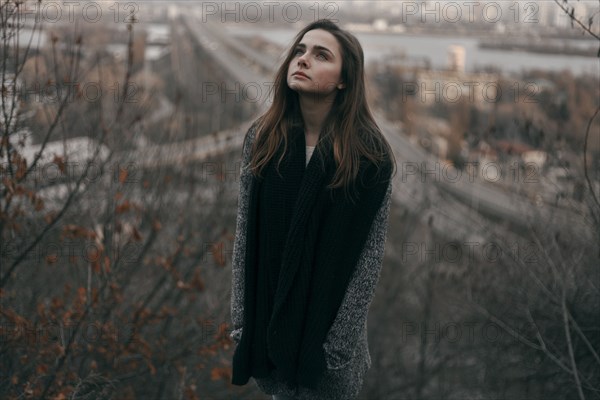 Portrait of pensive Caucasian woman standing on hill near freeway