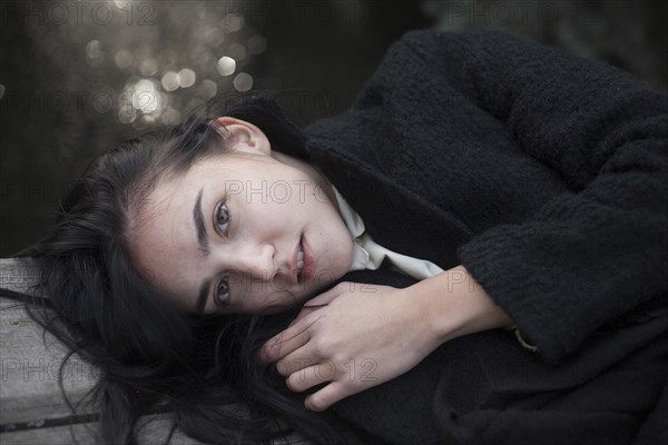 Portrait of serious Caucasian woman laying on wood