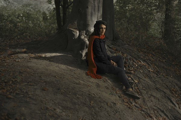 Portrait of Caucasian woman sitting on tree roots in forest