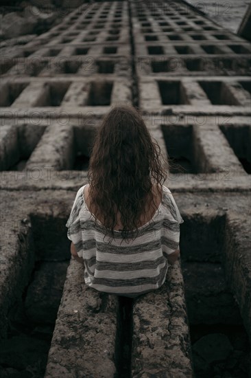 Rear view of Caucasian girl sitting on structure