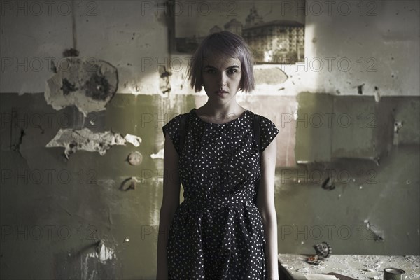 Serious Caucasian woman standing near dilapidated wall