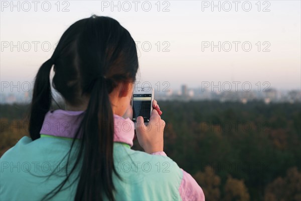 Woman photographing scenic view with cell phone