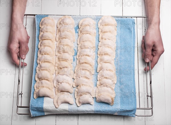 Hands holding rows of pierogies on towel