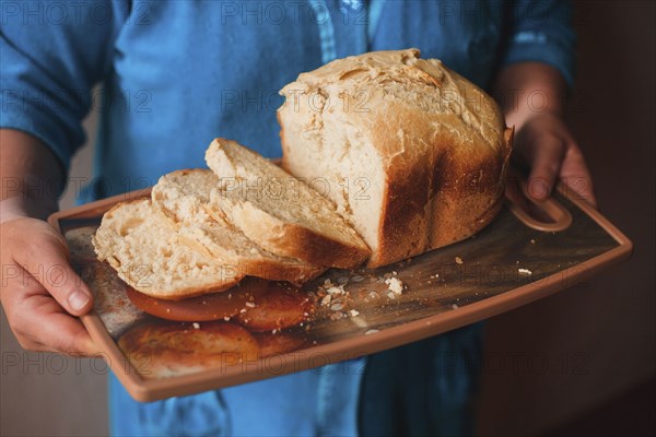 Hands holding tray of sliced bread