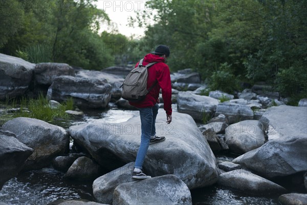 Caucasian man hiking on rocks in river