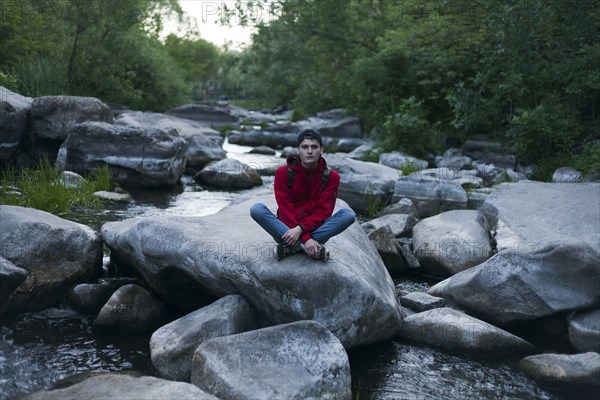 Caucasian man sitting on rock in river