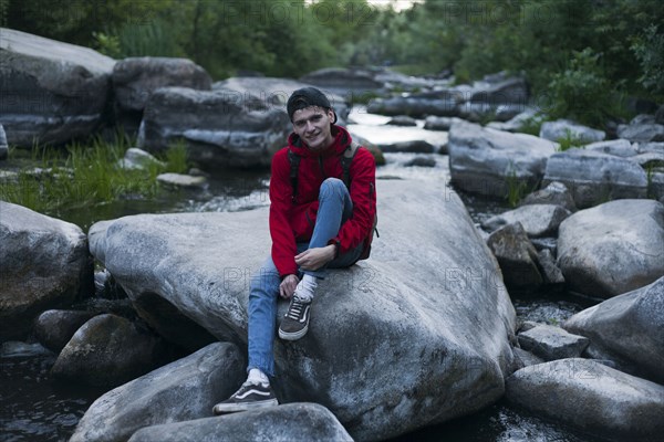 Caucasian man sitting on rock in river