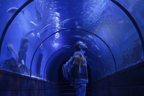 Caucasian man admiring fish in aquarium