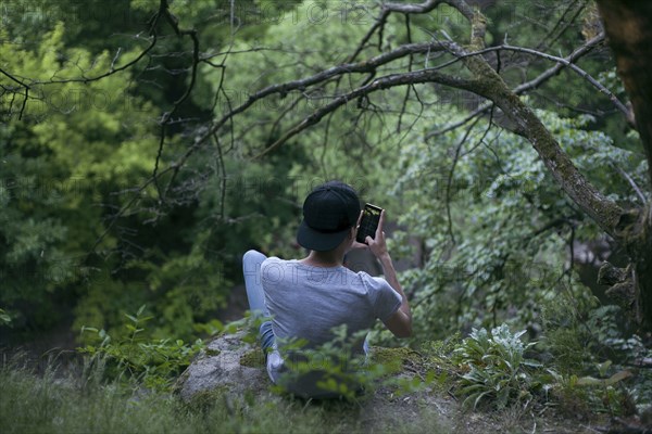 Caucasian man texting on cell phone in woods