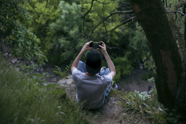 Caucasian man photographing with cell phone in woods
