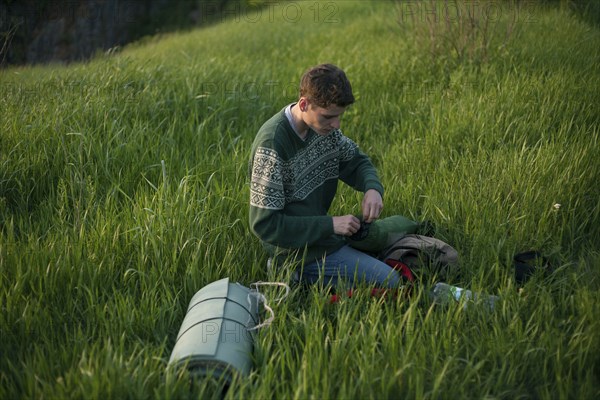 Caucasian hiker kneeling in grass