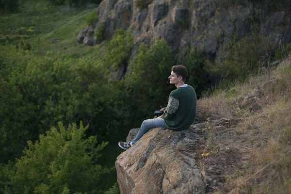 Caucasian man sitting on a rock admiring landscape