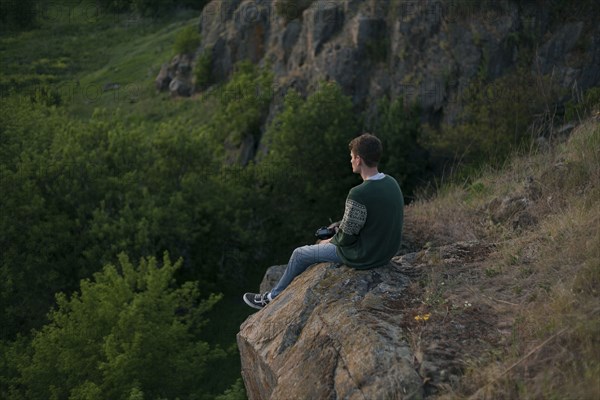 Caucasian man sitting on a rock admiring landscape