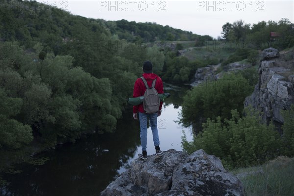 Caucasian hiker standing on rock near river