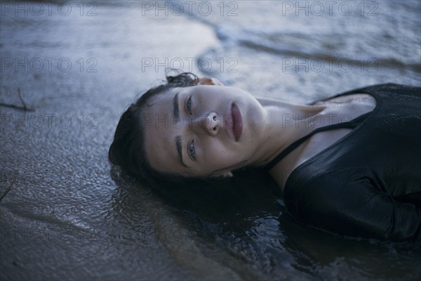 Caucasian woman laying on beach in waves