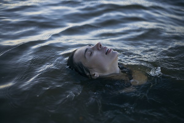 Caucasian woman floating in ocean with eyes closed