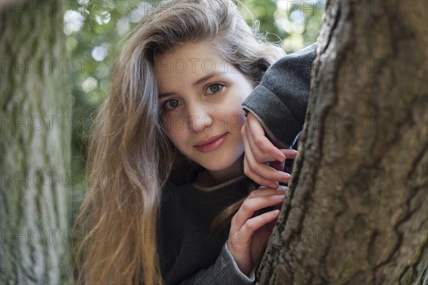 Portrait of smiling Caucasian teenage girl leaning on tree