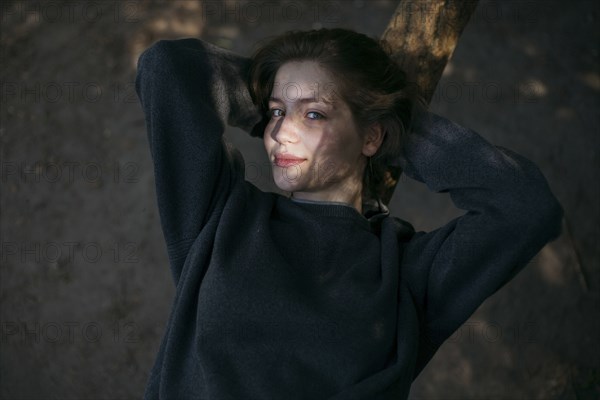 Portrait of smiling Caucasian teenage girl leaning on tree