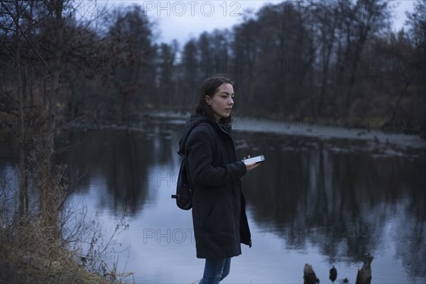 Caucasian woman holding cell phone near river