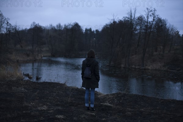 Caucasian woman standing near river at night