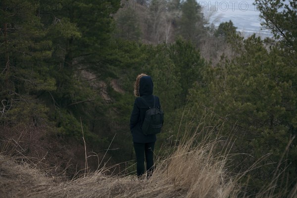 Caucasian woman standing near trees carrying backpack