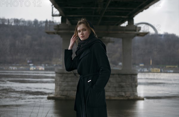 Caucasian woman standing under bridge near river