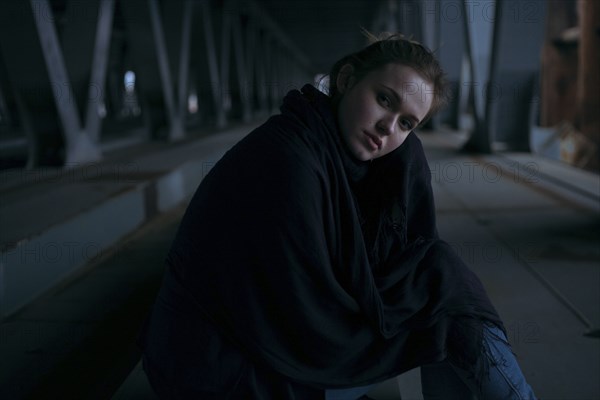 Caucasian woman sitting under bridge