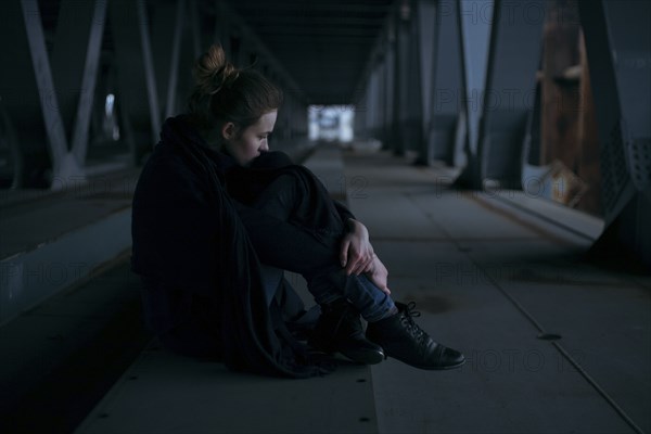 Caucasian woman sitting under bridge