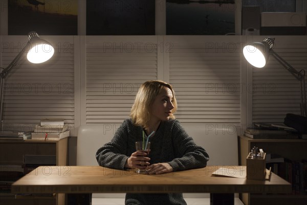 Caucasian woman sitting at desk drinking beverage