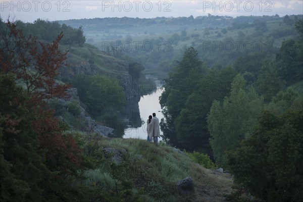 Caucasian couple standing on hill admiring river