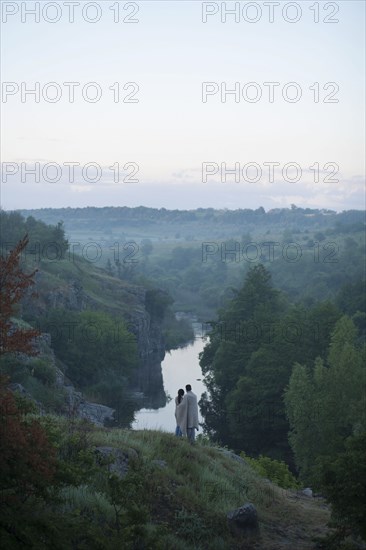 Caucasian couple standing on hill admiring river