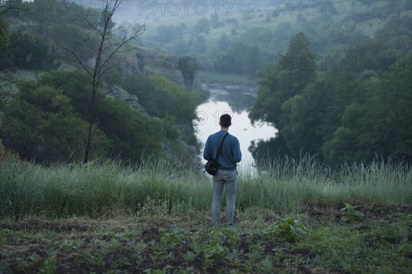 Caucasian man standing on hill above river