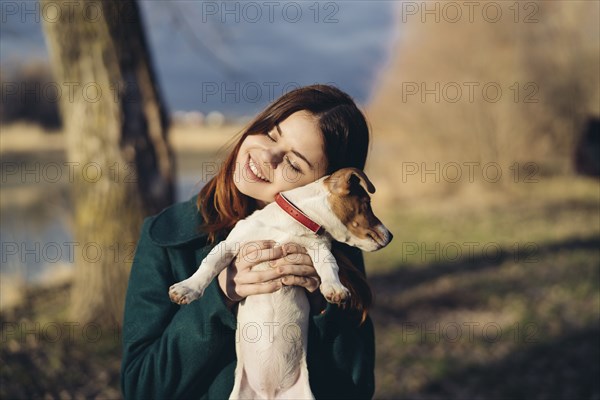 Caucasian woman lifting an hugging dog