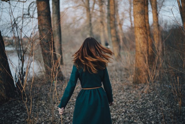 Caucasian woman walking near trees and river